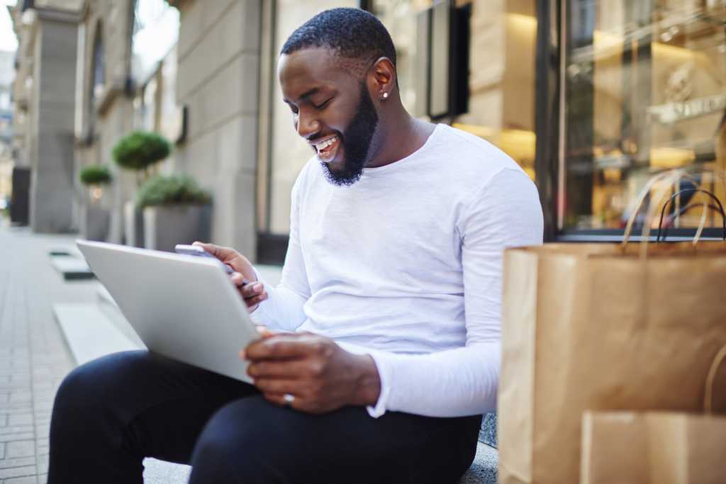 smiling male checking phone laptop on stoop rwd